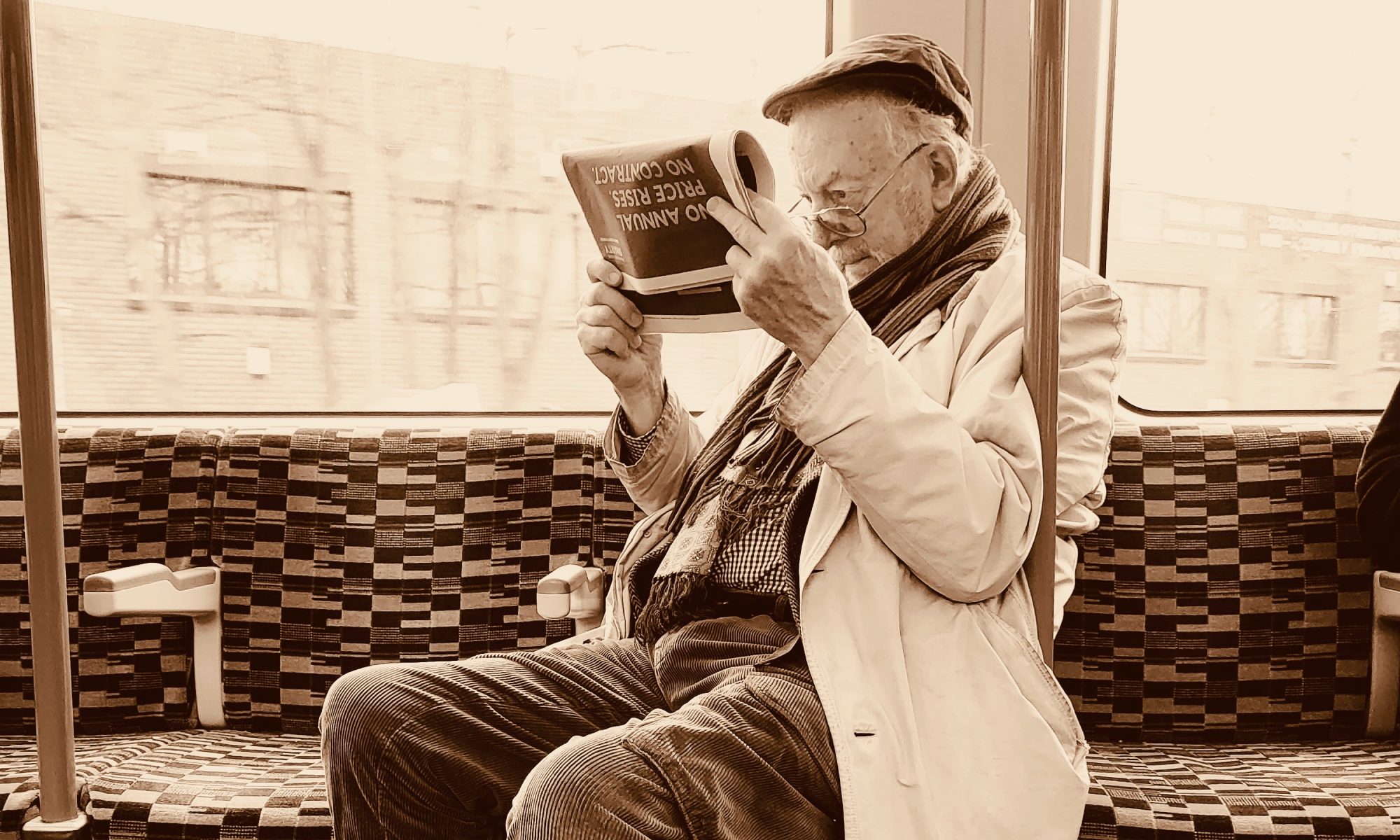 Alter Mann liest aufmerksam eine Zeitung in einem öffentlichen Verkehrsmittel