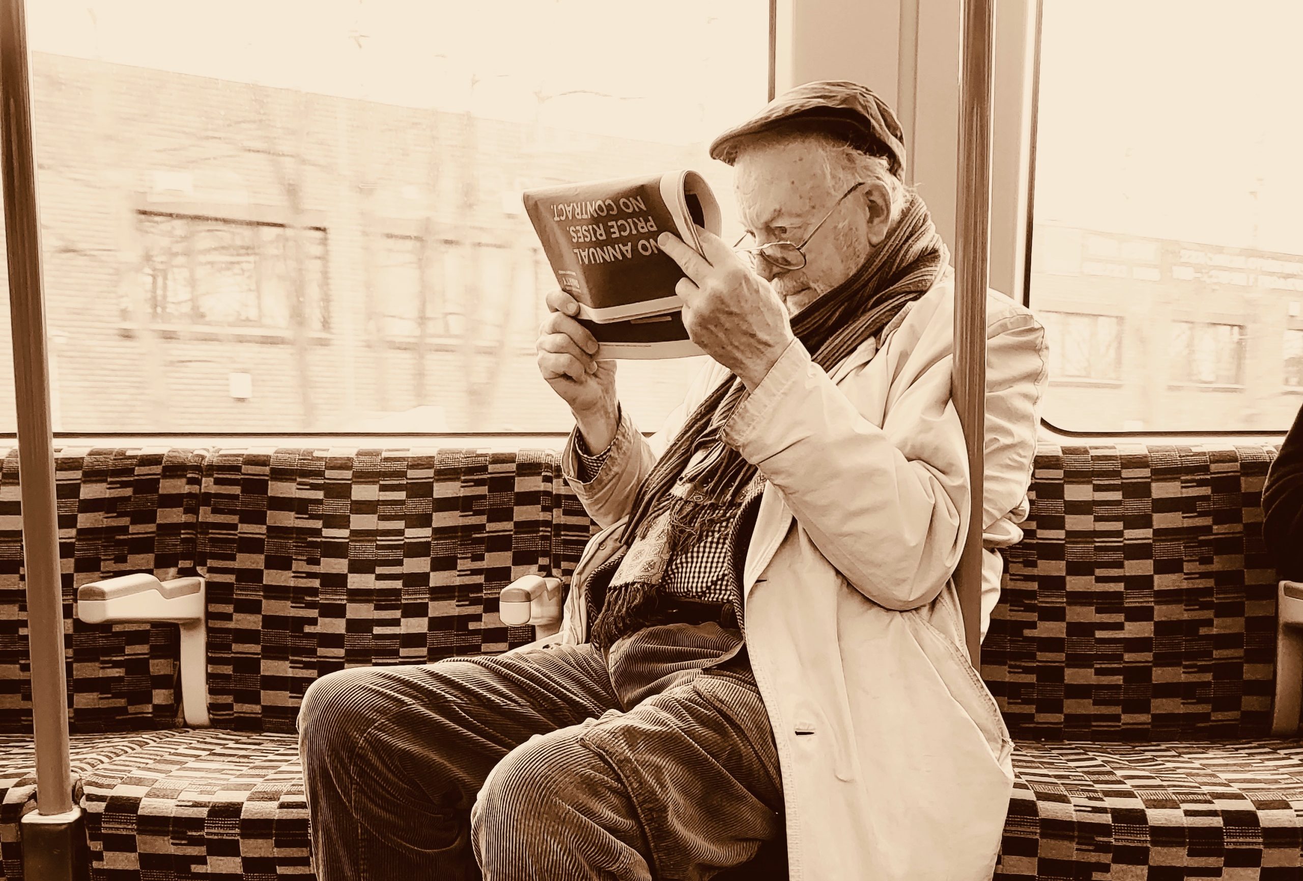 Alter Mann liest aufmerksam eine Zeitung in einem öffentlichen Verkehrsmittel